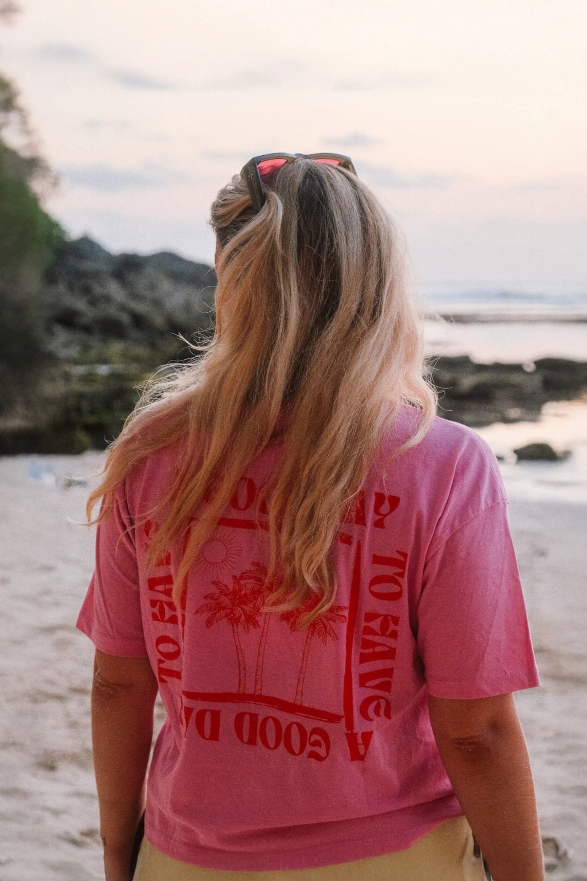 Lässiger Sommerlook am Strand – A Good Day Women T-Shirt Pink mit Palmendesign auf dem Rücken.