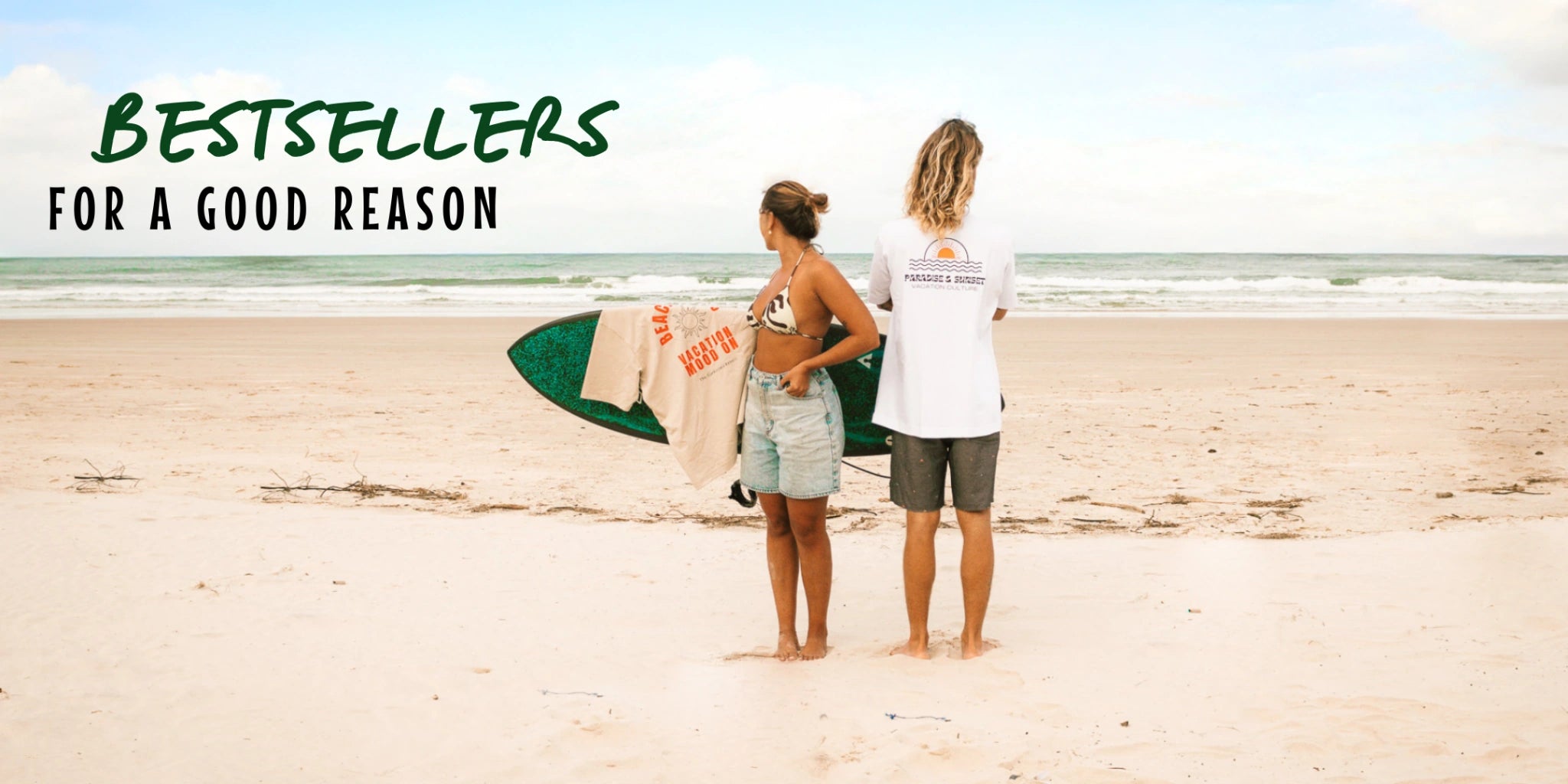 Frau mit Surfbrett und T-Shirt mit dem Aufdruck "Vacation Mood On" am Strand – Bestseller Strandmode für den Sommer.