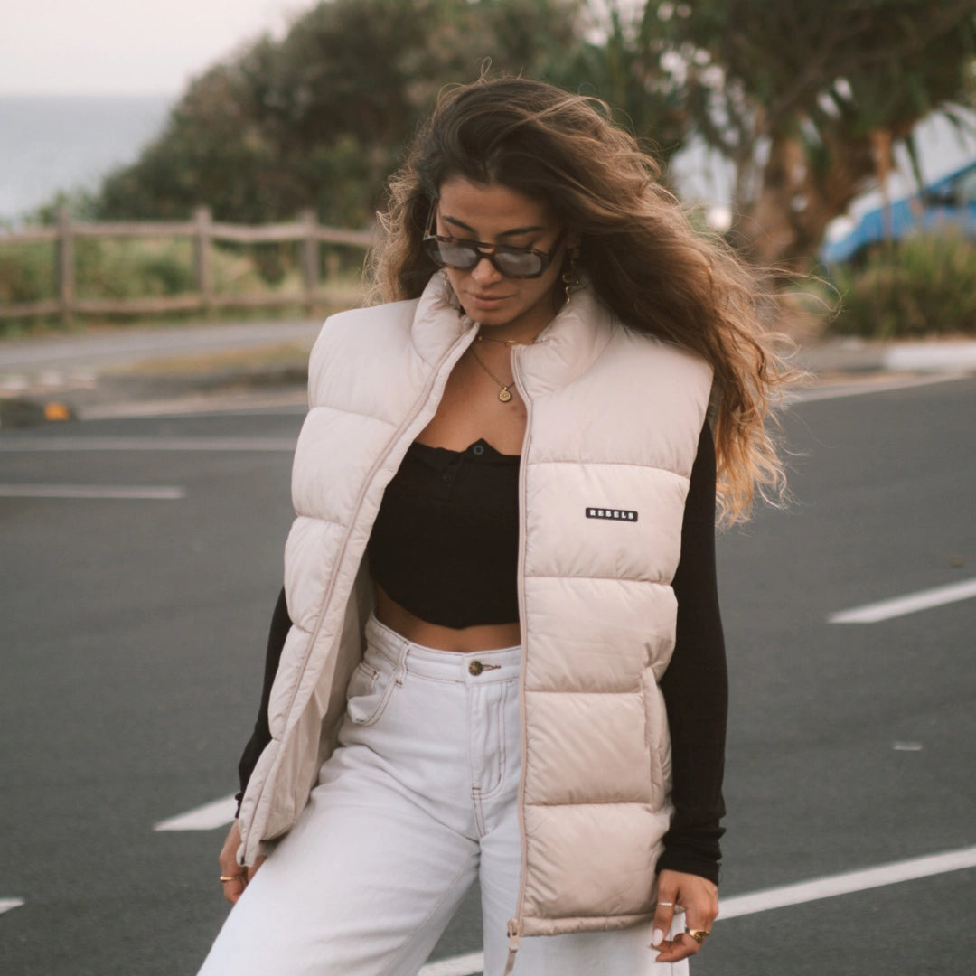 Frau trägt beige Puufer Weste und schaut auf den Boden