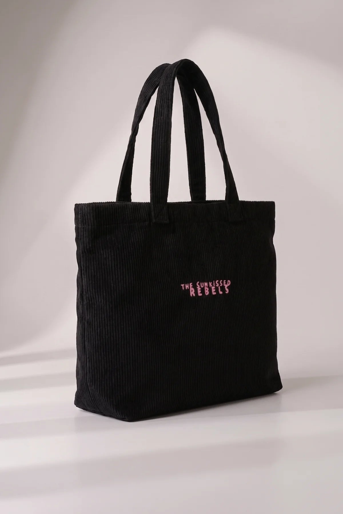 Seitenansicht der geräumigen schwarzen Cord Bag aus 100% Bio-Baumwolle mit Henkeln und Bodenfalte im Studio-Licht.