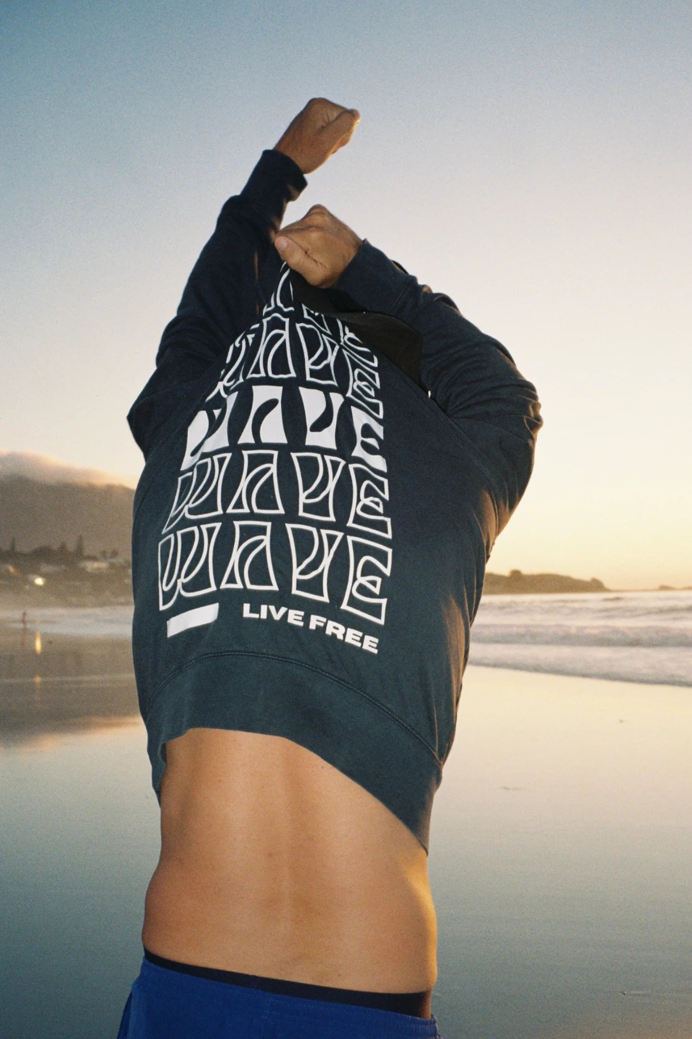 Live Free Vintage Sweater Black von hinten am Meer – minimalistisches Design und nachhaltige Mode