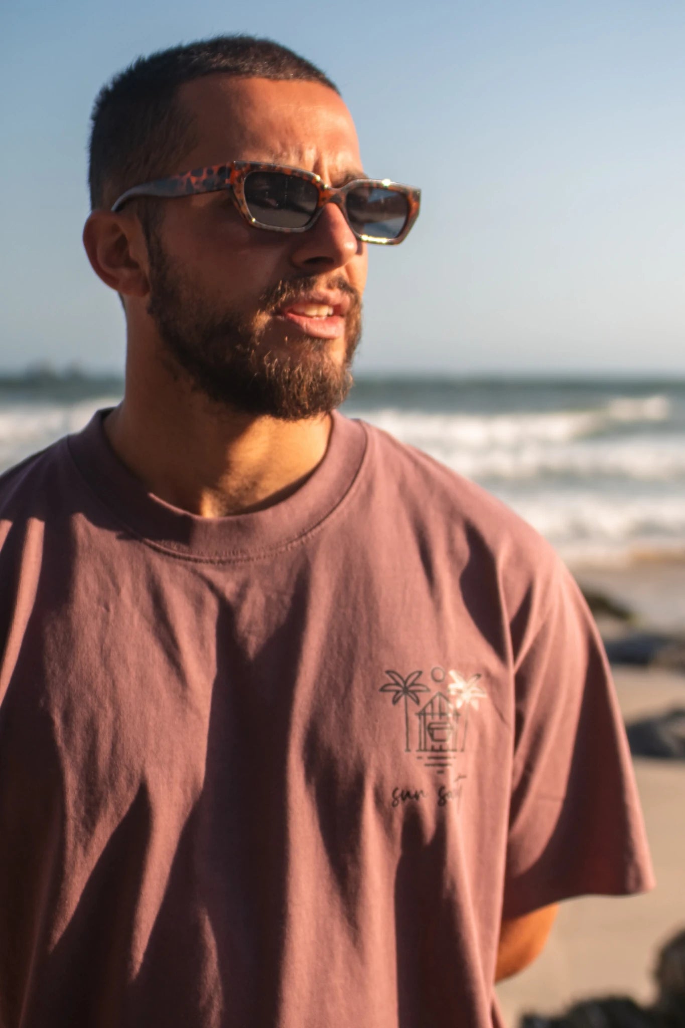 Detailansicht des Oversized T-Shirt Açaí Sun Society mit Sun Society Print am Strand