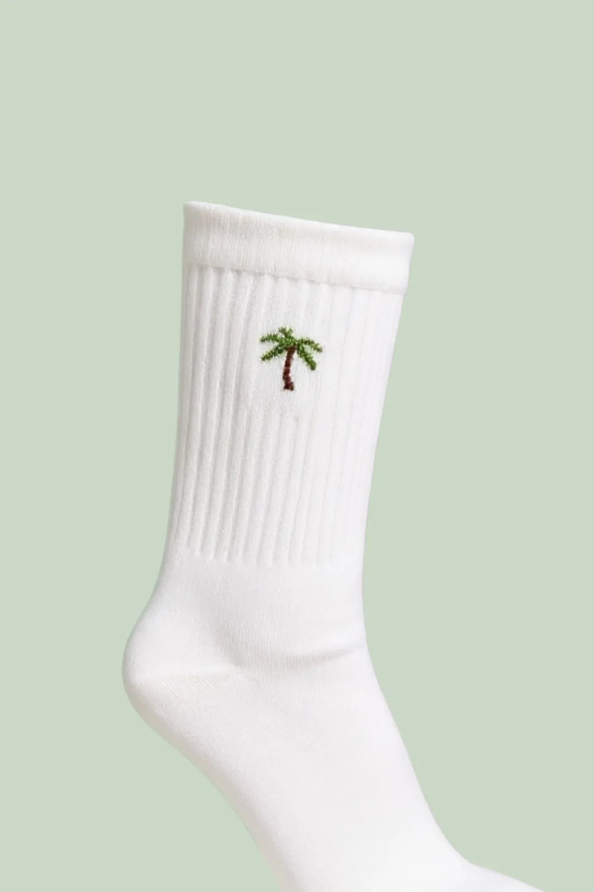 Detailaufnahme der weißen Tennissocken mit Palmenstickerei am gerippten Schaft.