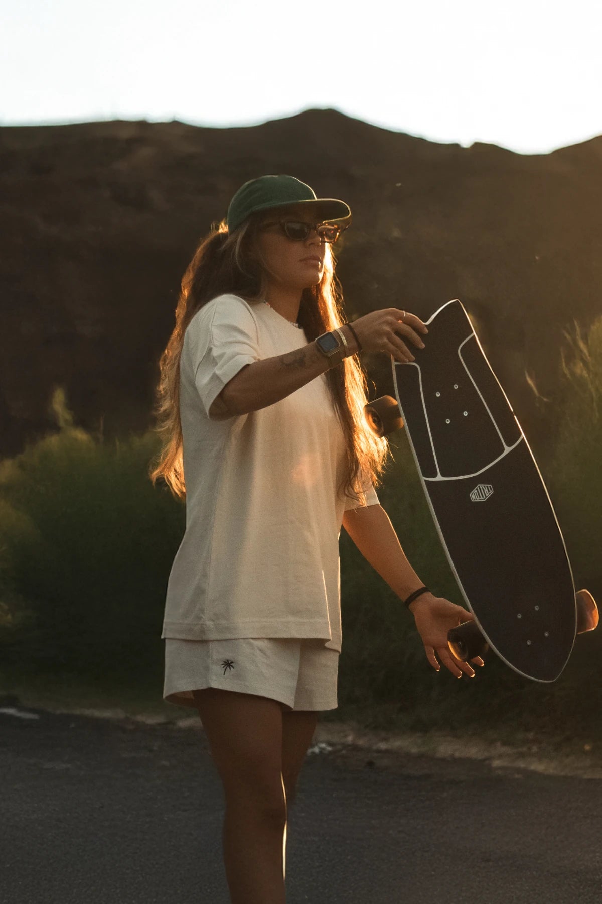 Skateboarderin in Naturtönen bei Sonnenlicht mit Longboard