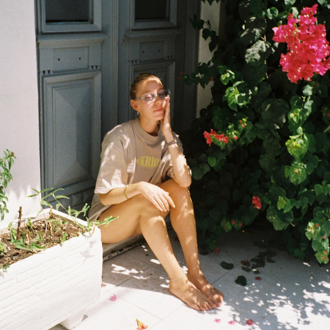 Entspannter Sommerlook – Frau im SNKRBLS Oversized T-Shirt Stone auf einer sonnigen Veranda