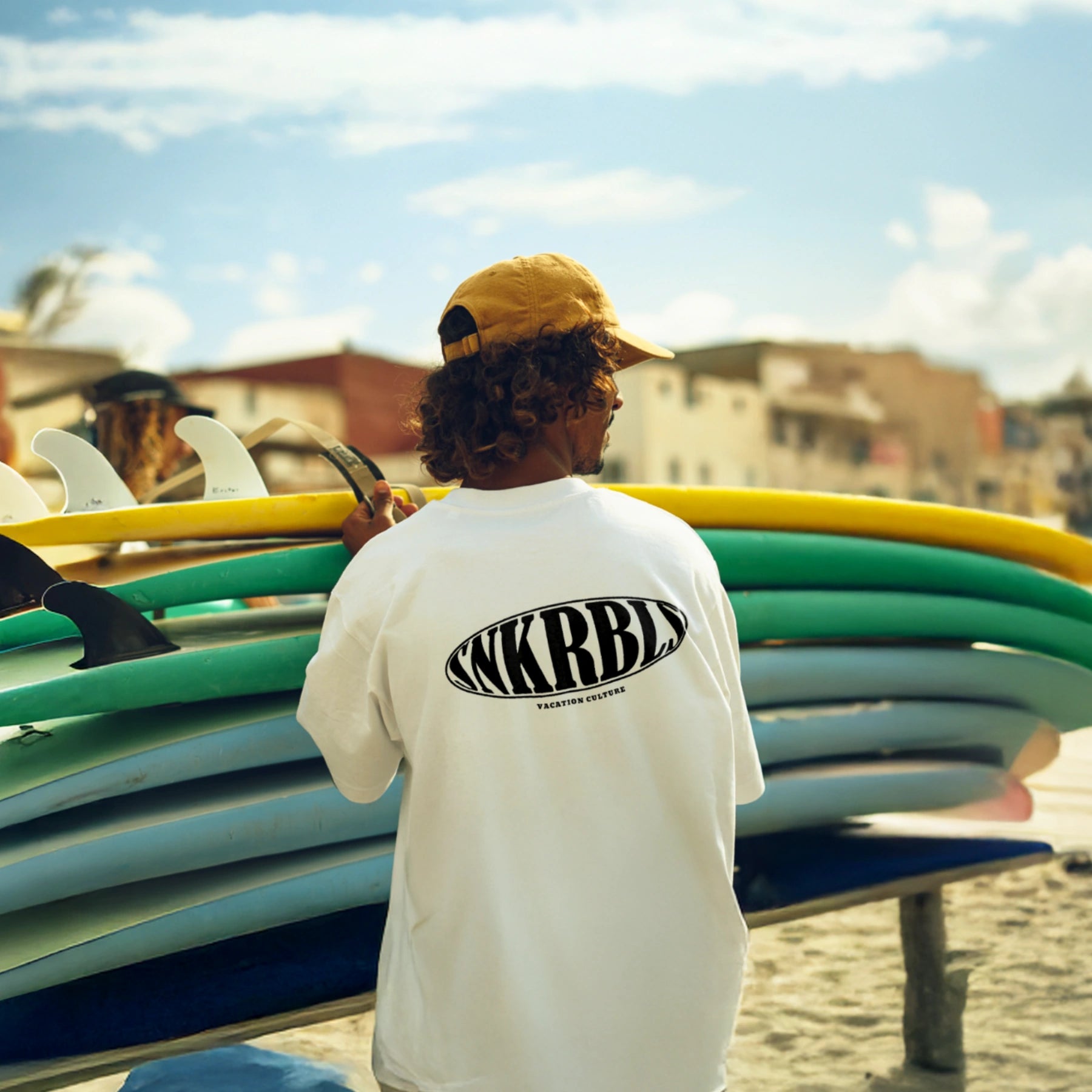 SNKRBLS Shirt in Weiß – Surfermoment mit Boards am Strand, sommerlicher Lifestyle-Vibe im quadratischen Format