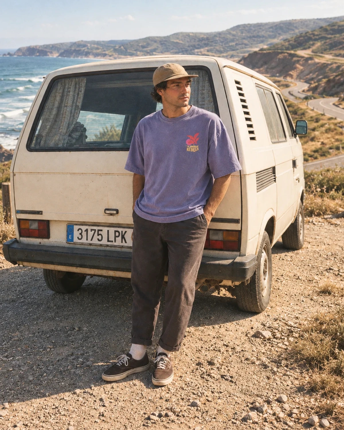 Mann trägt das Sunkissed Rebels Heavy Tee in Vintage Violet mit Oversized Fit und dezentem Brustprint an einem Camper an der Küste.