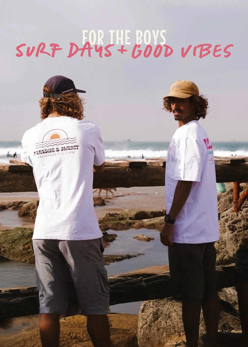 Zwei Surfer in stylischen T-Shirts am Strand mit Wellen im Hintergrund – ideal für entspannte Strandtage