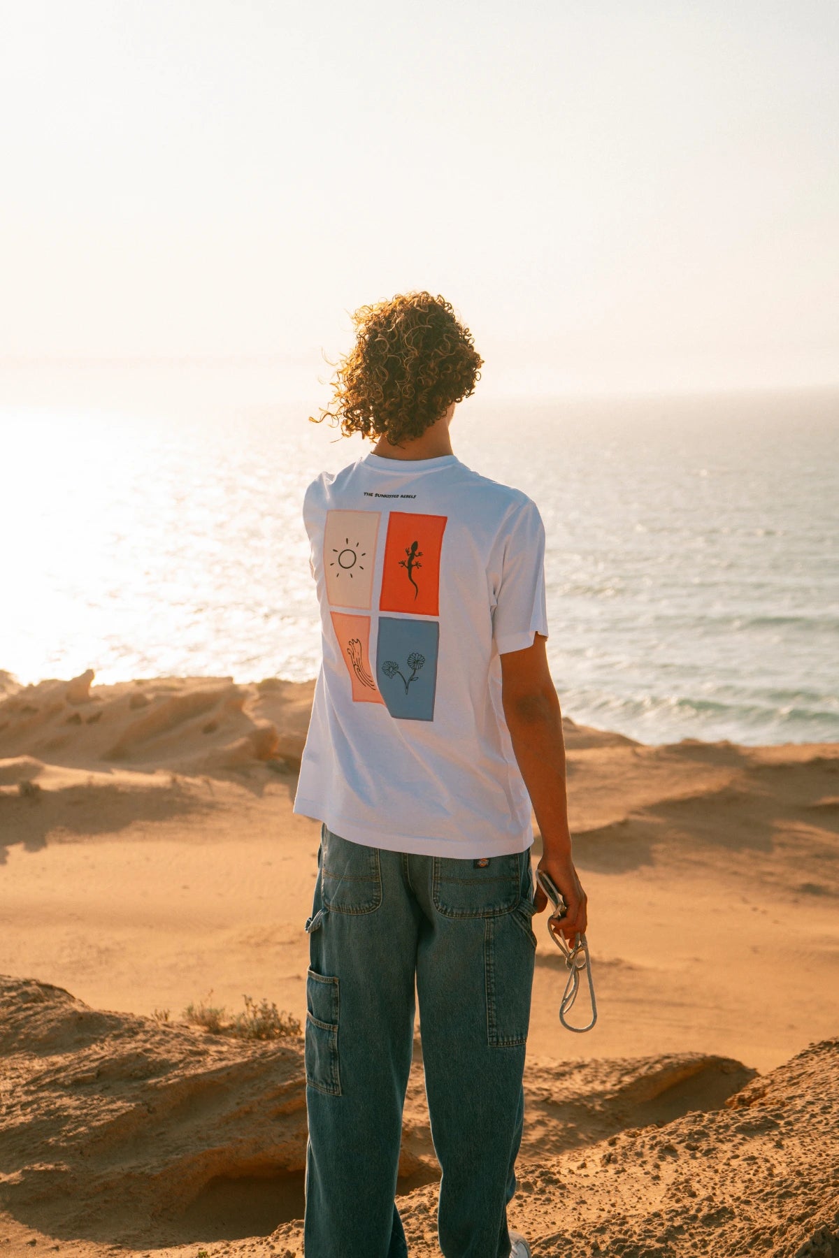 The Rebel Elements T-Shirt White Backprint getragen am Meer Sonnenuntergang Lifestyle Sommer
