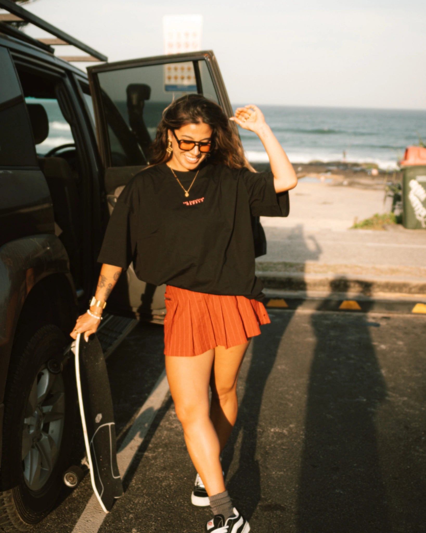 Schwarzes Oversized T-Shirt von The Sunkissed Rebels mit Skateboard im Sonnenuntergang