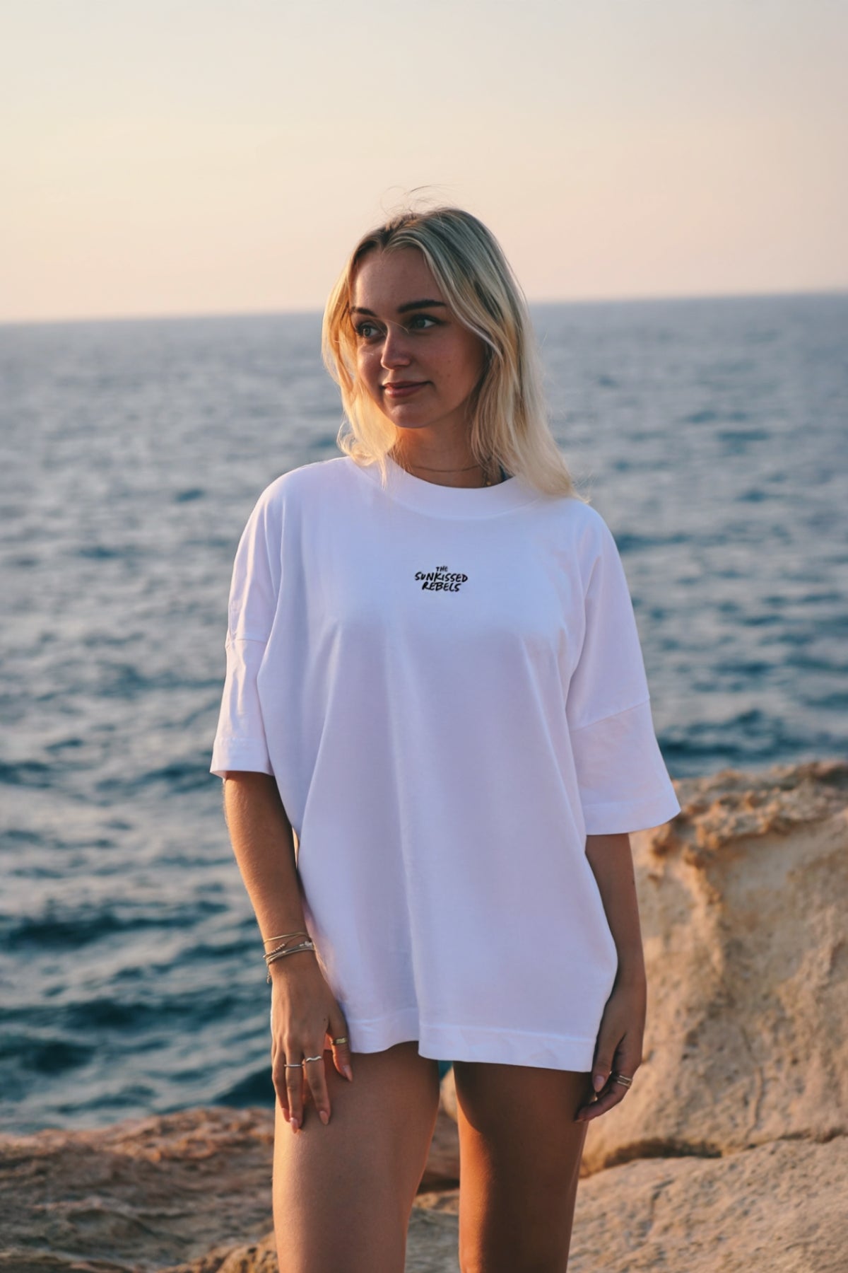 Frau steht am strand und trägt weißes oversized T-Shirt