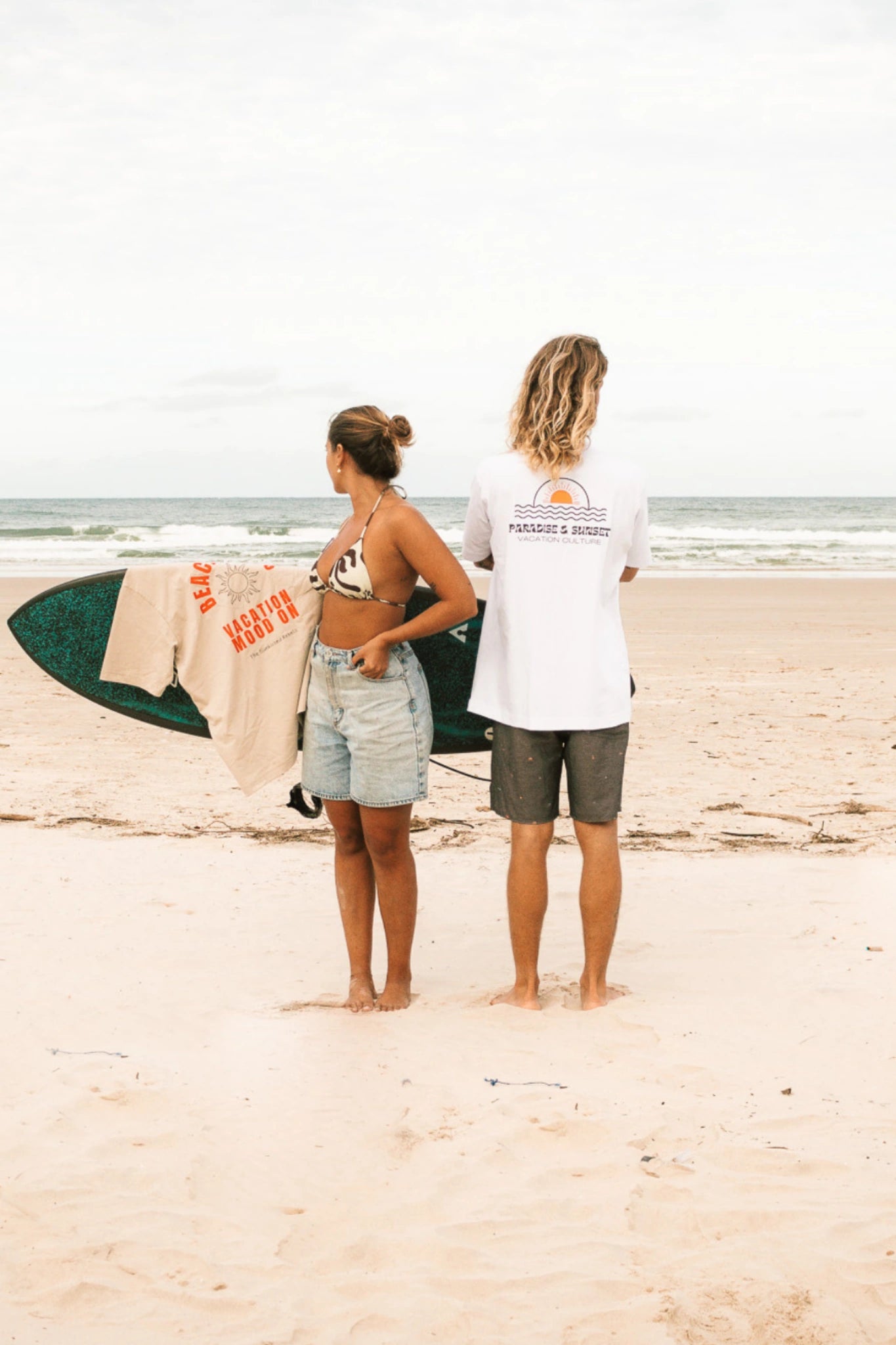Weißes T-Shirt „Paradise & Sunsets“ von The Sunkissed Rebels mit Backprint am Strand – nachhaltige Surf & Beach Streetwear.