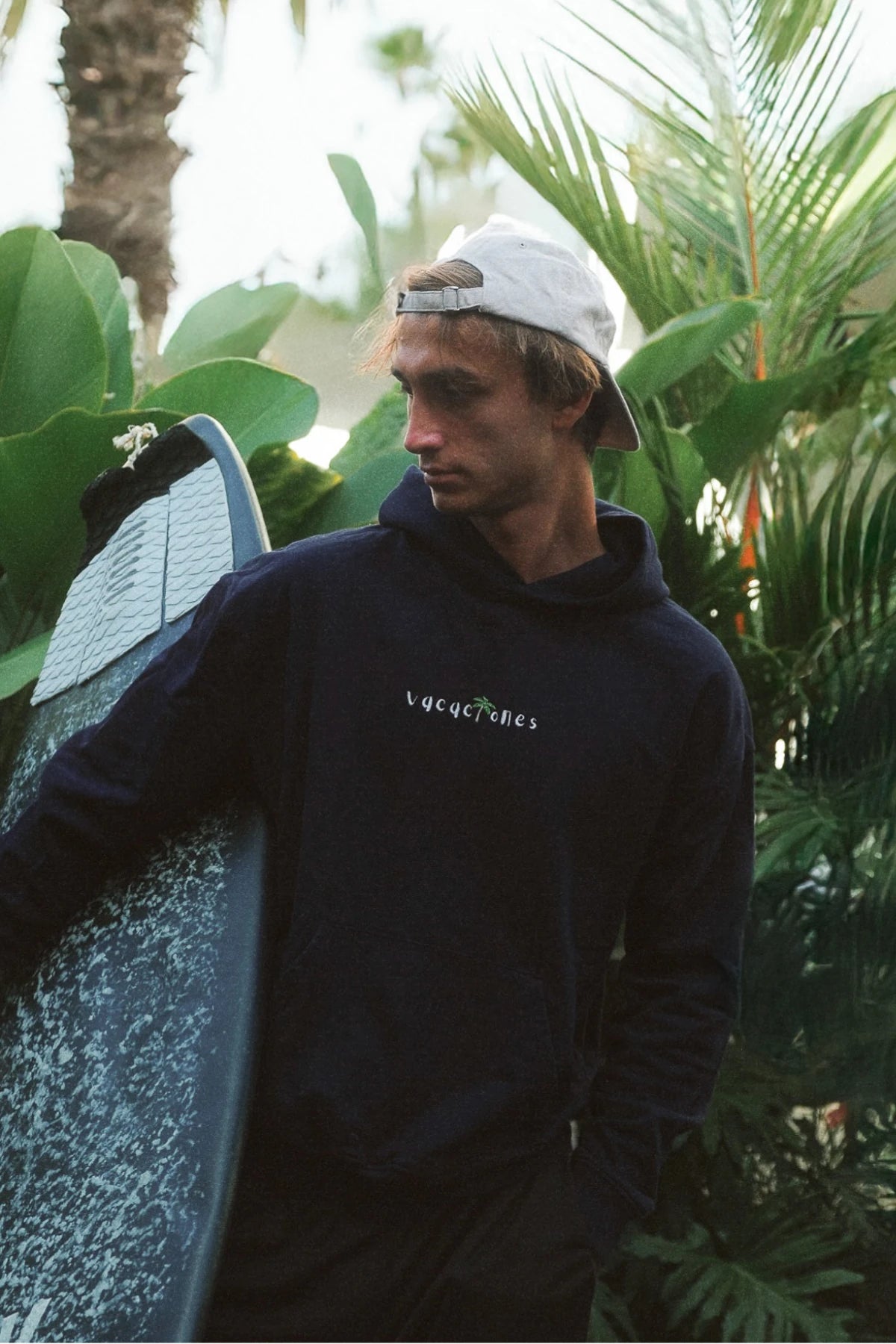 Surfer trägt den Vacaciones Hoodie Dark Ocean – komfortabler Kapuzenpullover für Strandtage und Freizeit.