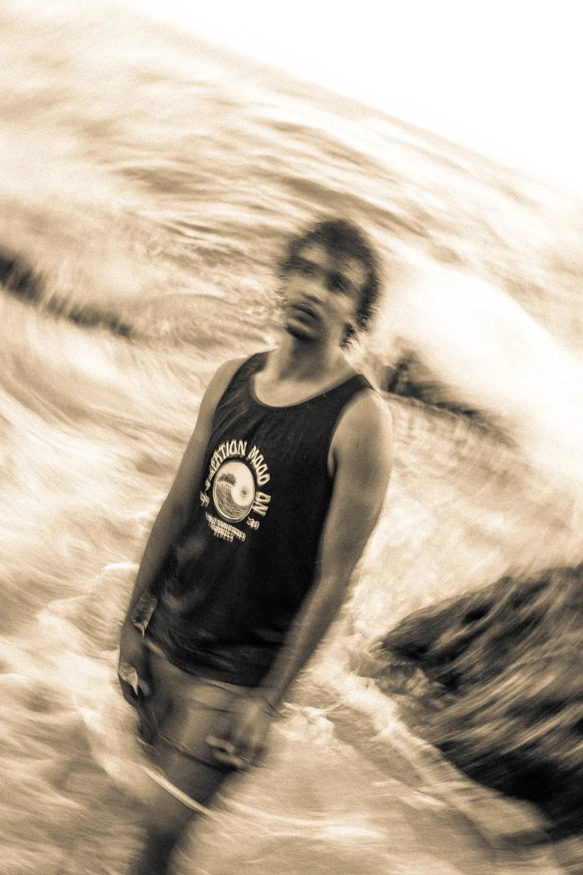 Mann am Strand mit Vacation Mood On Tanktop in Schwarz, künstlerisch unscharf